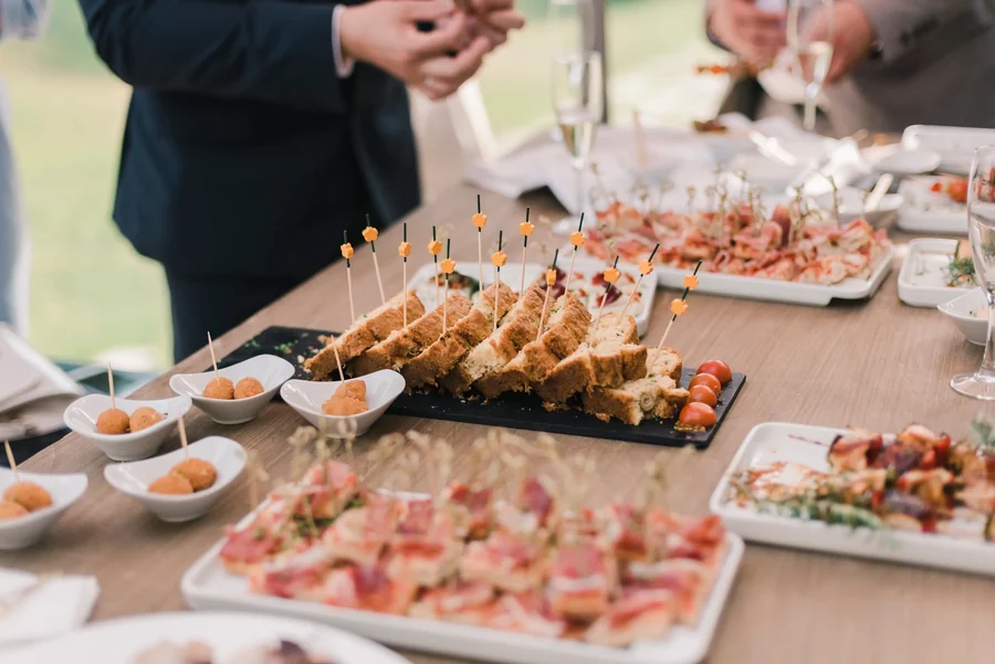 Buffet de cocktail dînatoire : ardoises de cakes salés piqués de mini-drapeaux, croquettes en coupelles, planches de charcuterie et flûtes de champagne.
